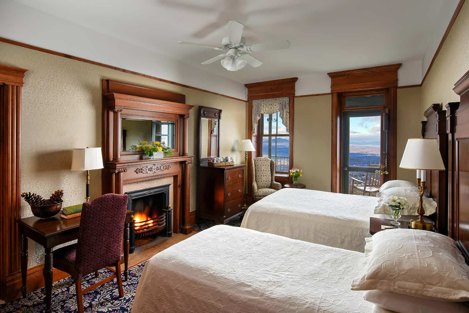 Mohonk Mountain House Accommodations that have 2 double beds. There is a fireplace and and small desk on the other side of the room. There is a balcony that has the Hudson Valley View