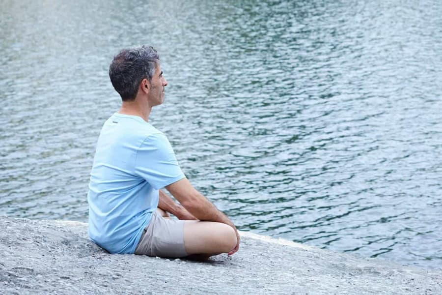 Man meditating by lake